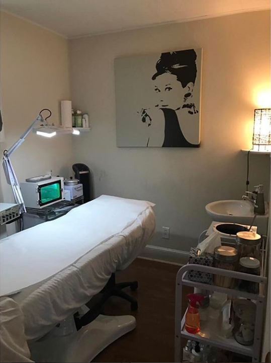 treatment room showing white table with bright lighting, Hepburn painting hanging on the wall